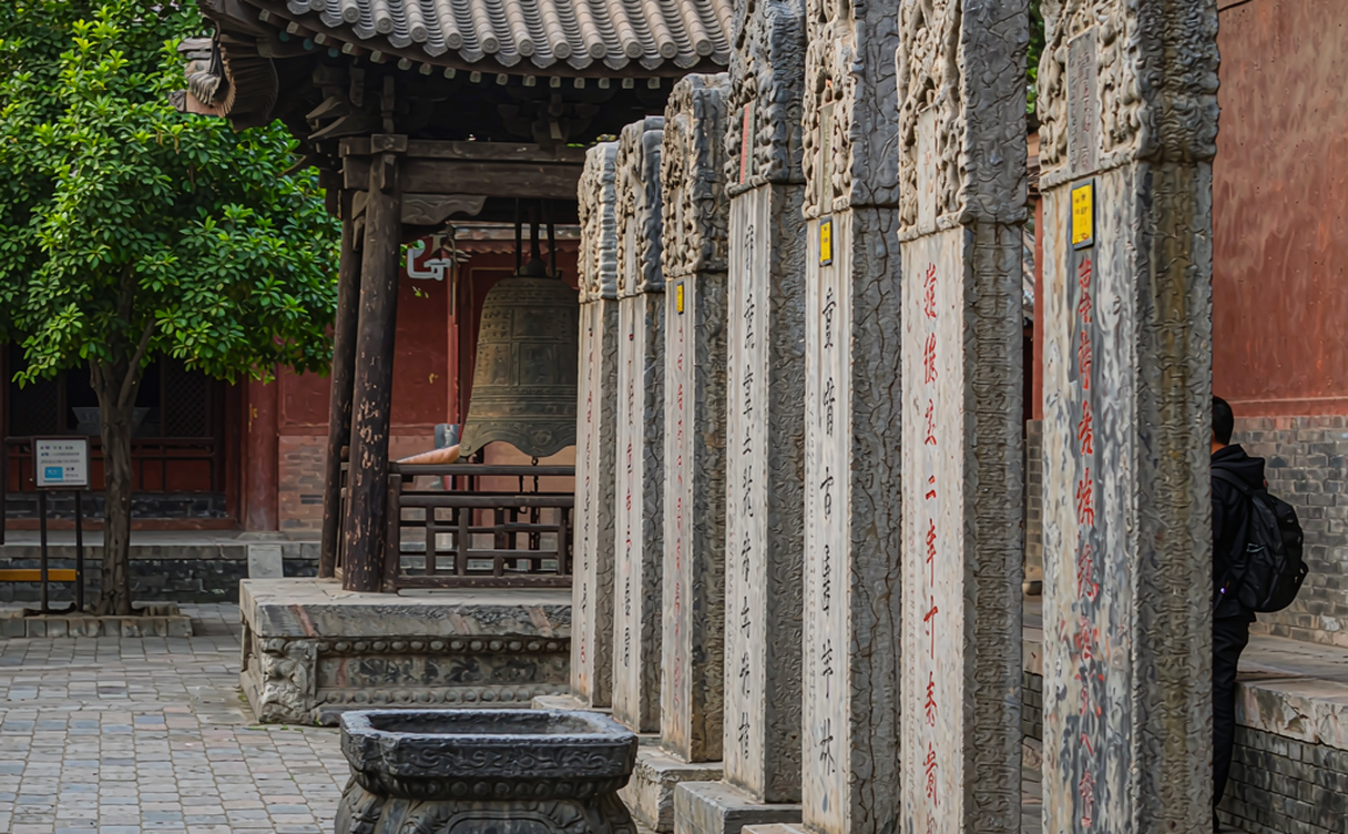 Devotee lighting incense sticks in front of the carved wooden hall at Fayuan Temple Beijing
