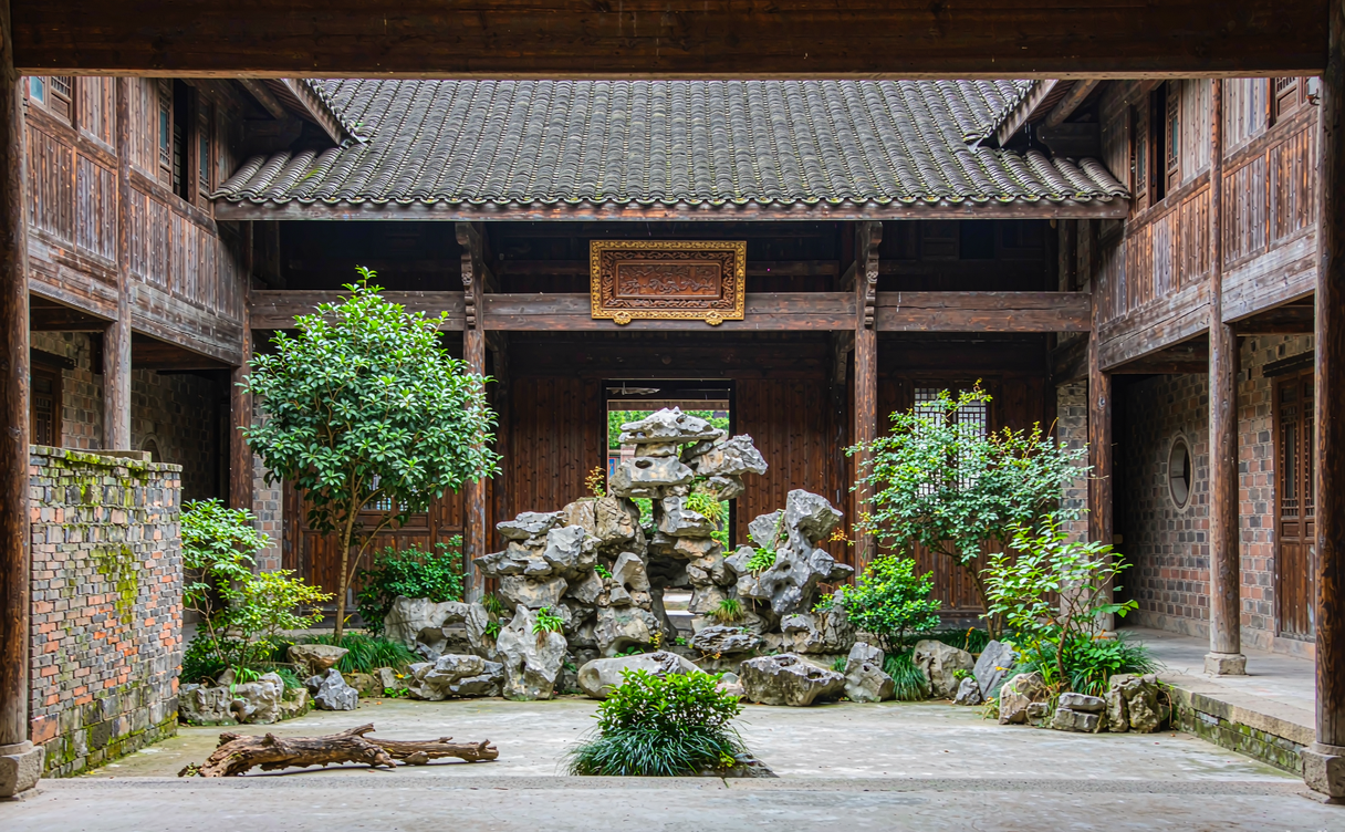 Restored Beijing courtyard hotel room with wooden beams opening to a small garden