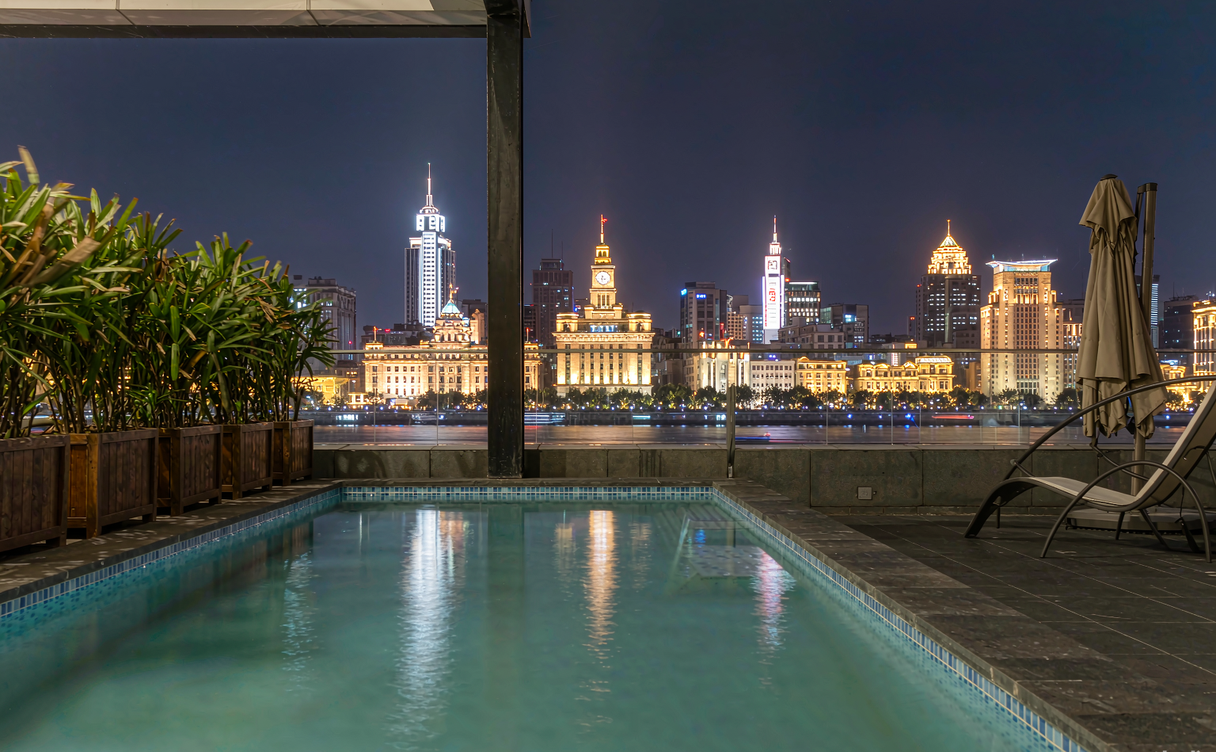Rooftop pool with view of the lit Bund and Pudong skyline in Shanghai at night