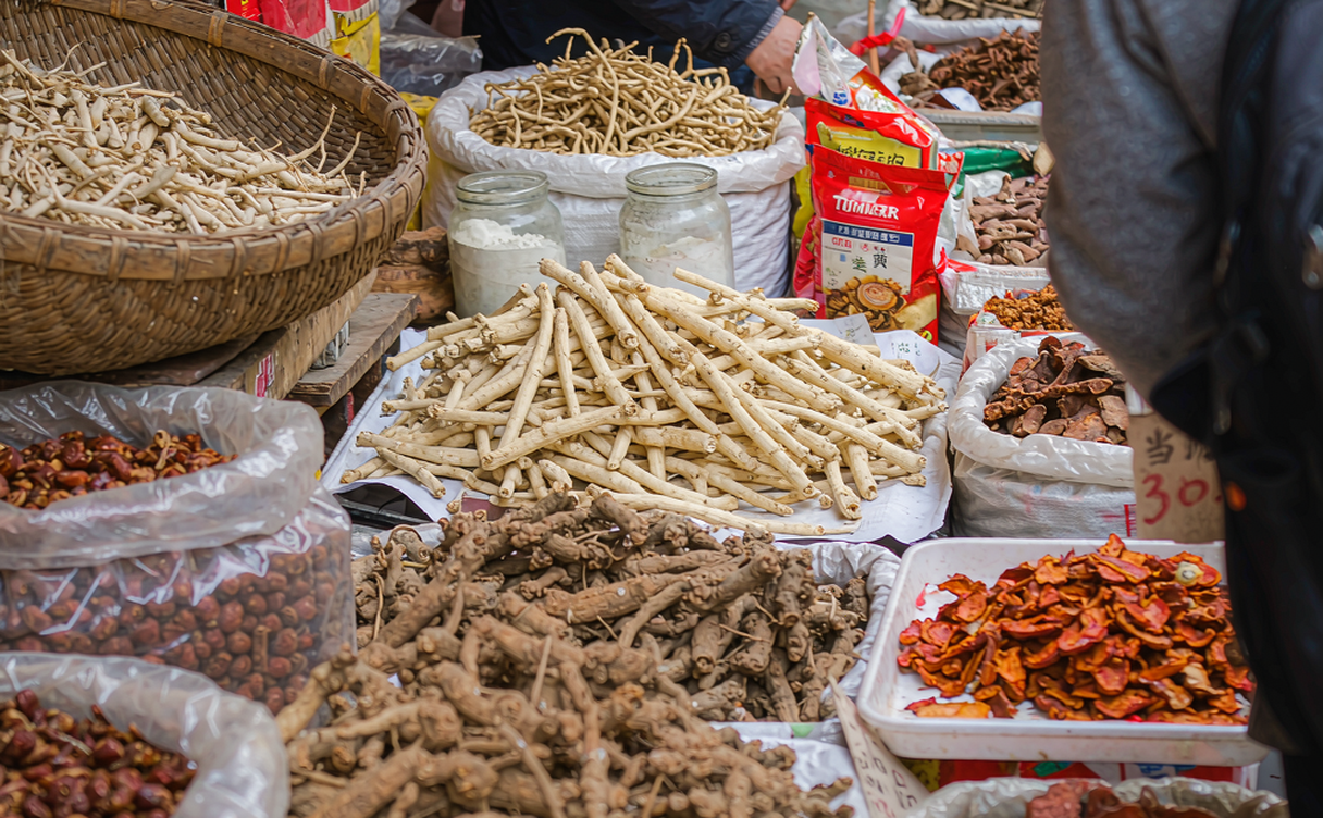 The vast Bozhou herb market with stalls of dried roots, bark, and spices under bright daylight