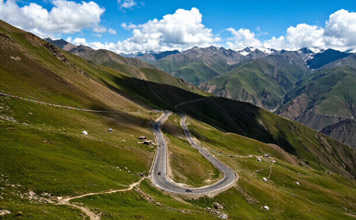 Mountain pass switchback road with alpine meadows and cloud shadows in Xinjiang China