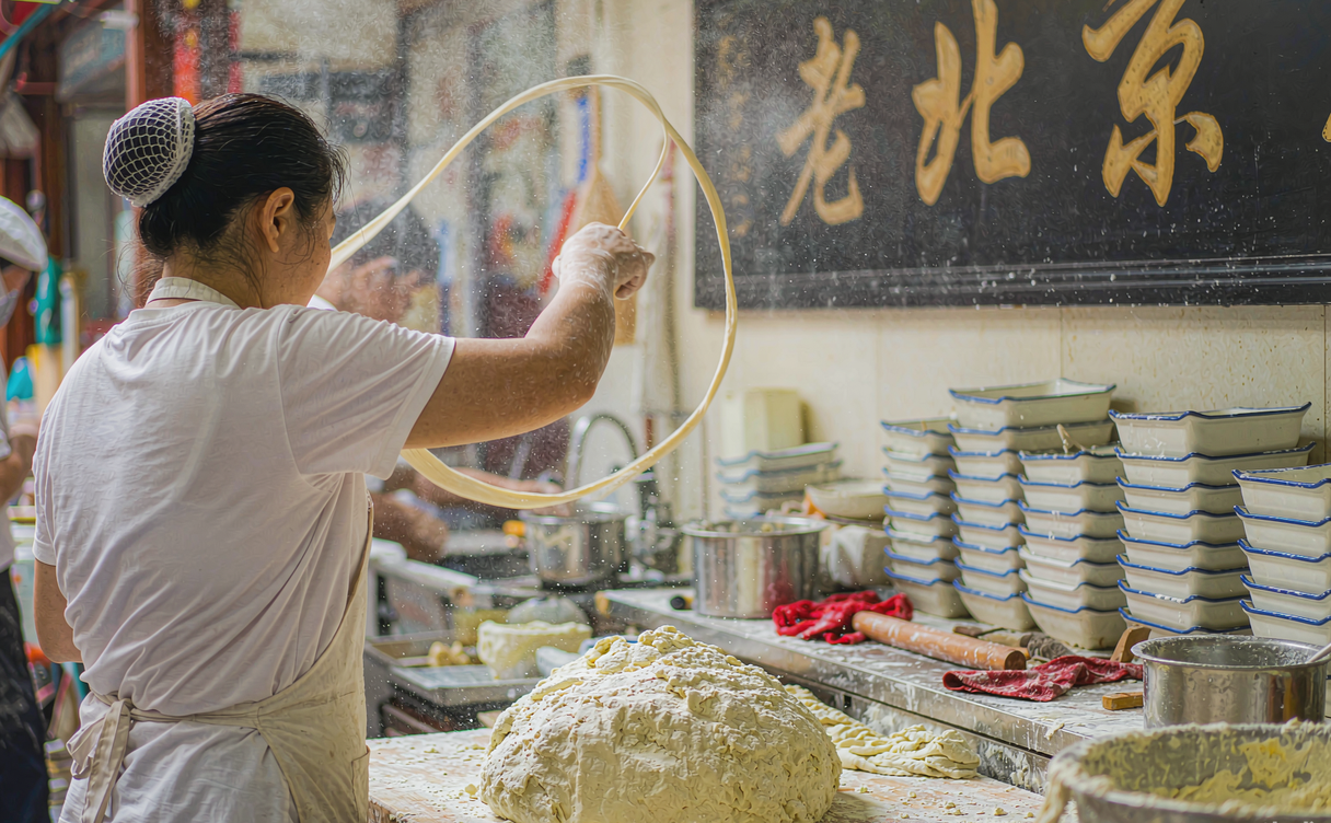 china-regional-noodles-guide - chef hand-pulling wheat noodles in an open kitchen