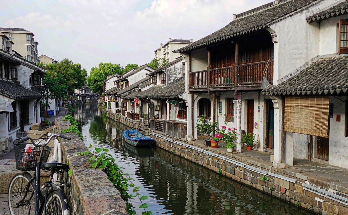 Visitor cycling through a quiet water town canal street near Shanghai