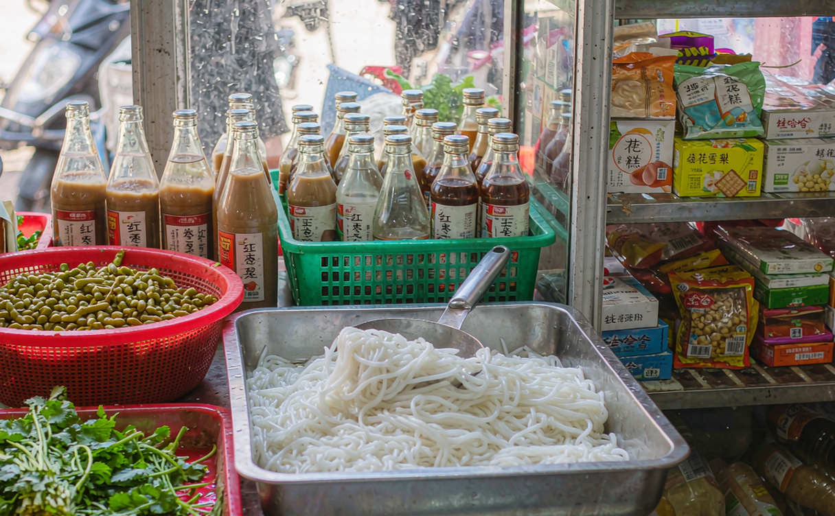 A Guangxi street food stall with steaming bowls of rice noodles topped with fresh herbs
