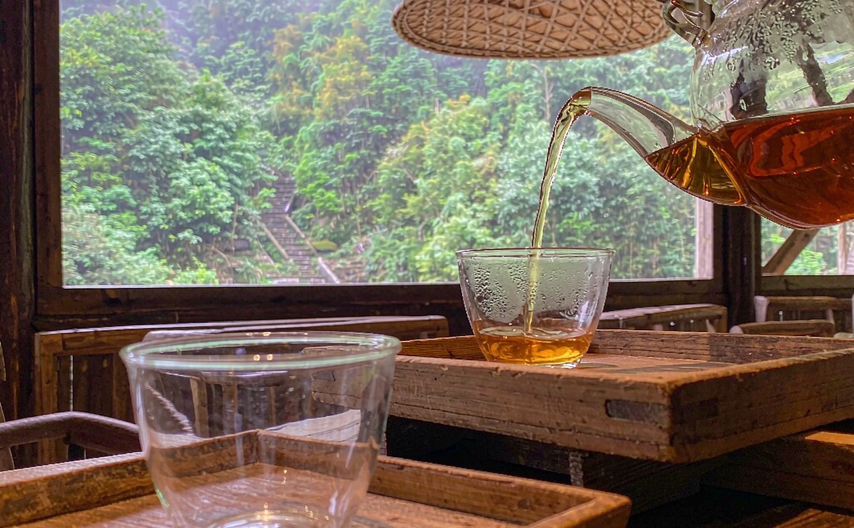 Tea farmer hand-panning Longjing tea leaves in a wok over charcoal