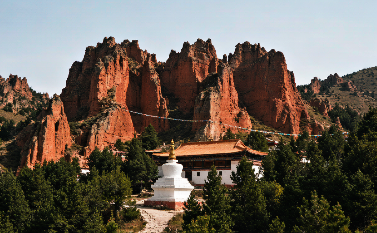 Kanbula National Park travel guide - hillside monastery and stupa among red Danxia pillars