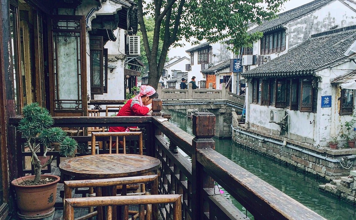 Lantern-lit stone bridge over the Pingjiang canal at dusk in Suzhou