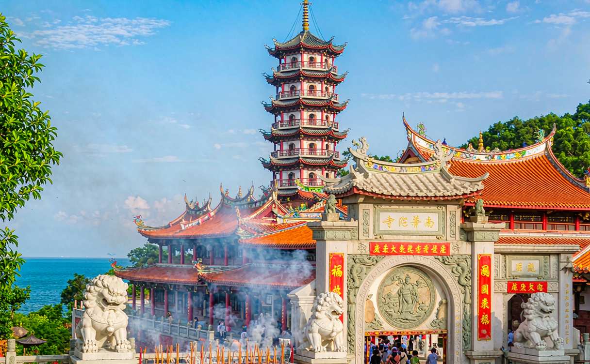 Layered golden temple halls of Nanputuo Temple rising against the green Wulao Peak