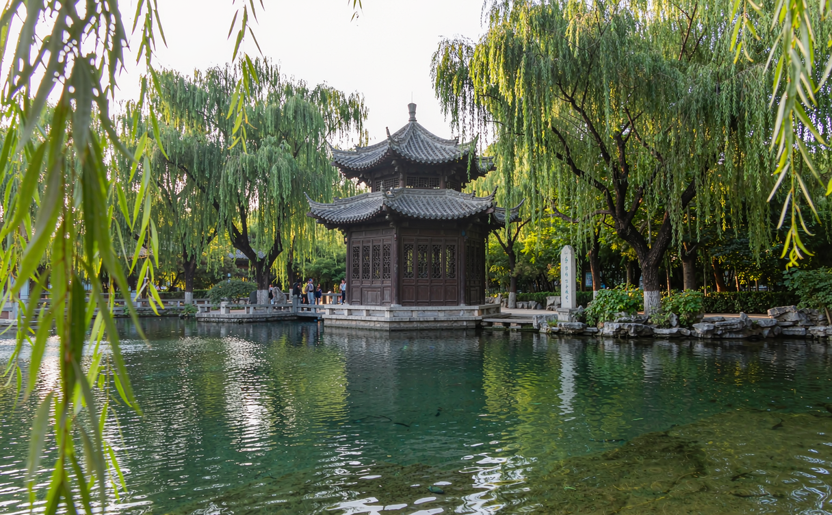 Stele pavilion and weeping willow trees surrounding the Baotu Spring pool in Jinan