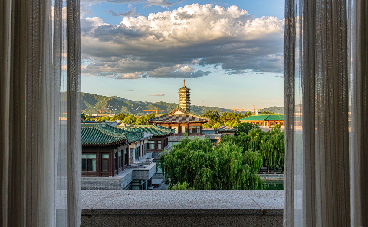 Hotel window view over the tiled rooftops of the Chengde Mountain Resort at golden hour