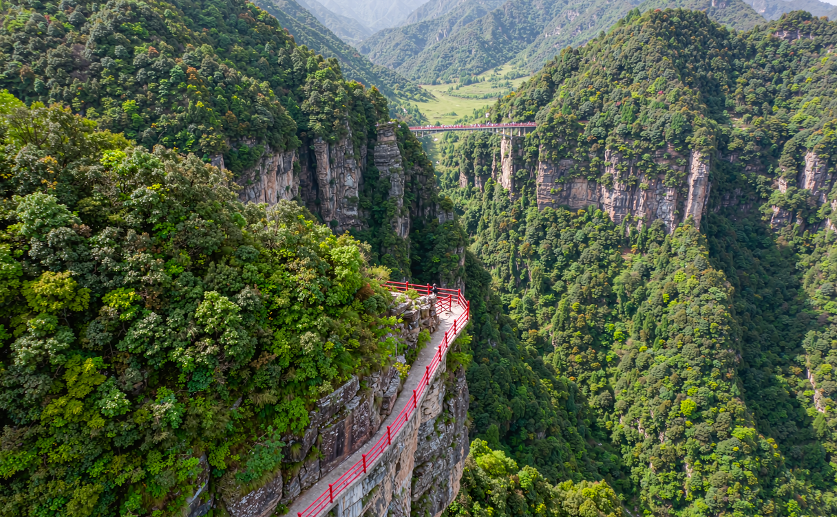 Narrow cliffside walkway with red railings crossing the Cangyan Mountain gorge in Hebei