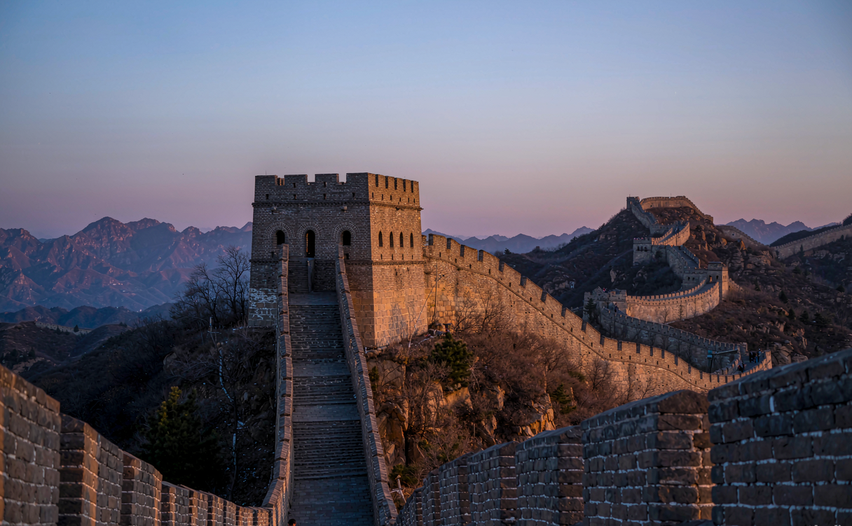 Tourists walking the restored Mutianyu Great Wall at sunrise under a clear sky