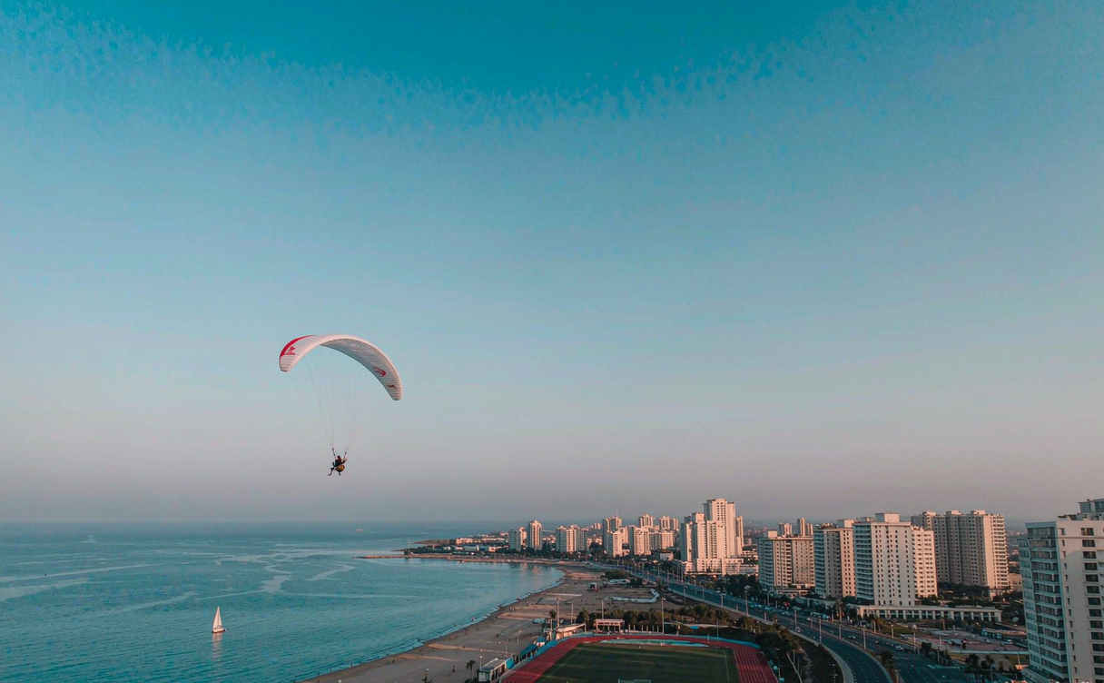 Colorful paragliders on a grassy landing field at sunset in China