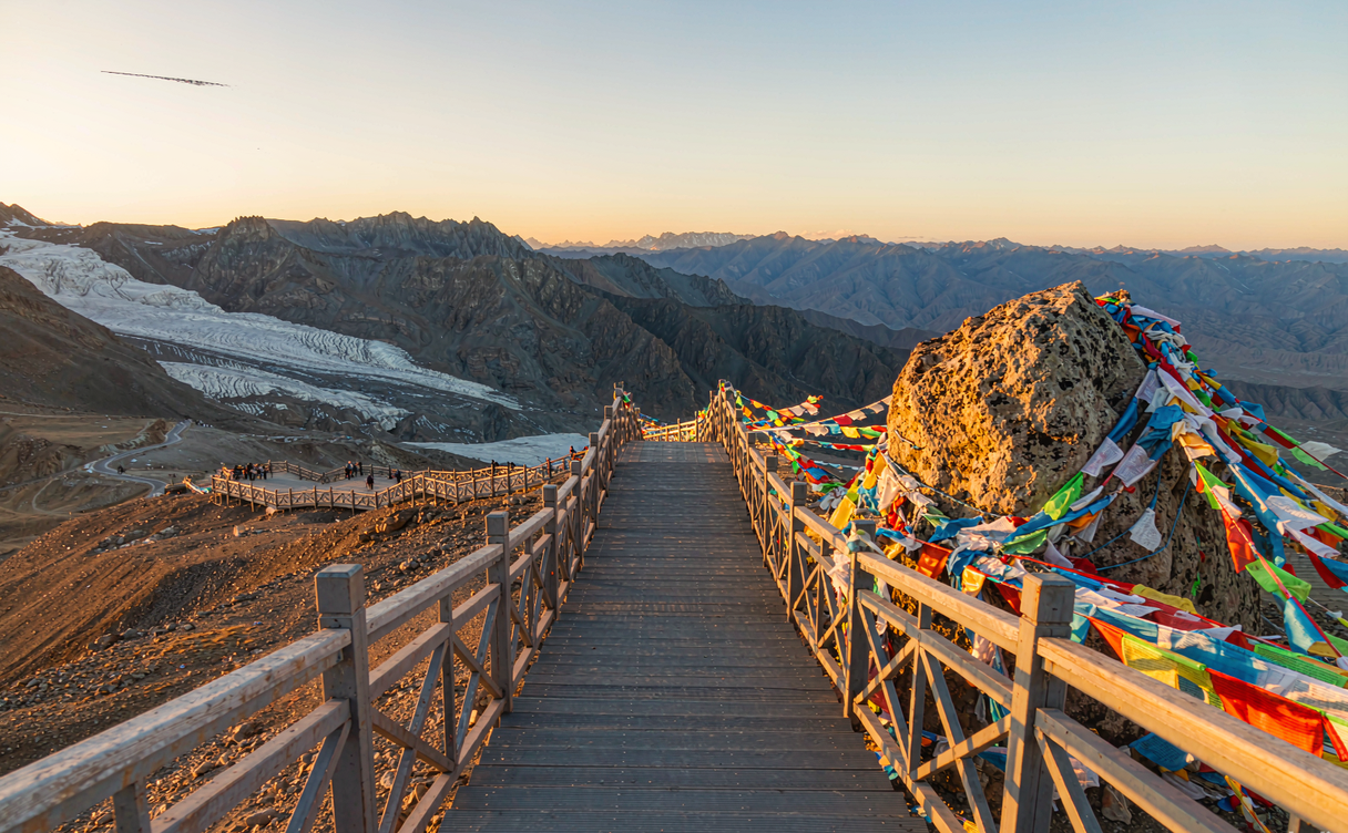 Prayer flags and wooden boardwalk on the windswept Dagu Glacier summit platform at 4,860 metres in Sichuan, China