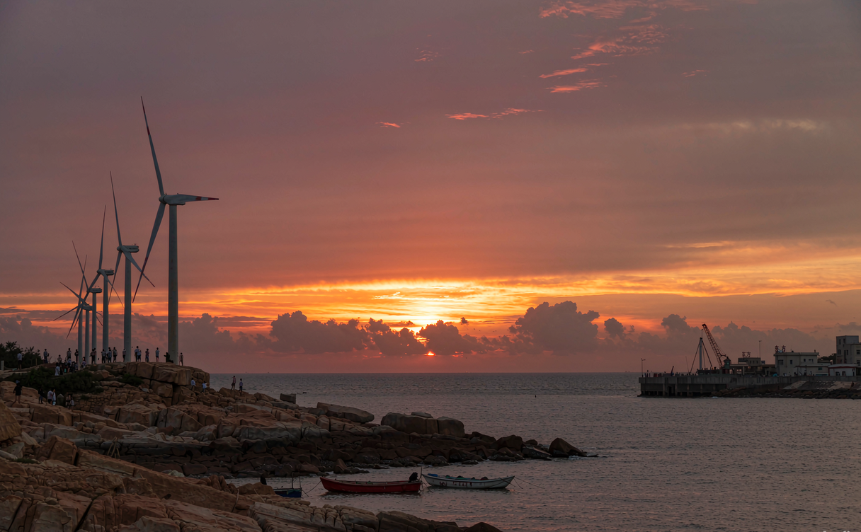 Sunset over the rocky coastline and wind turbines near Dongfang, Hainan