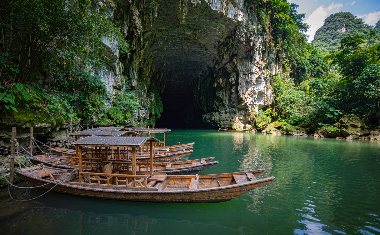 Wooden boats and Miao boatmen at the Getu River cave entrance in Guizhou