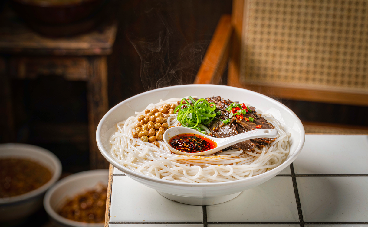 Bowl of dry-tossed Guilin rice noodles with peanuts and braised pork