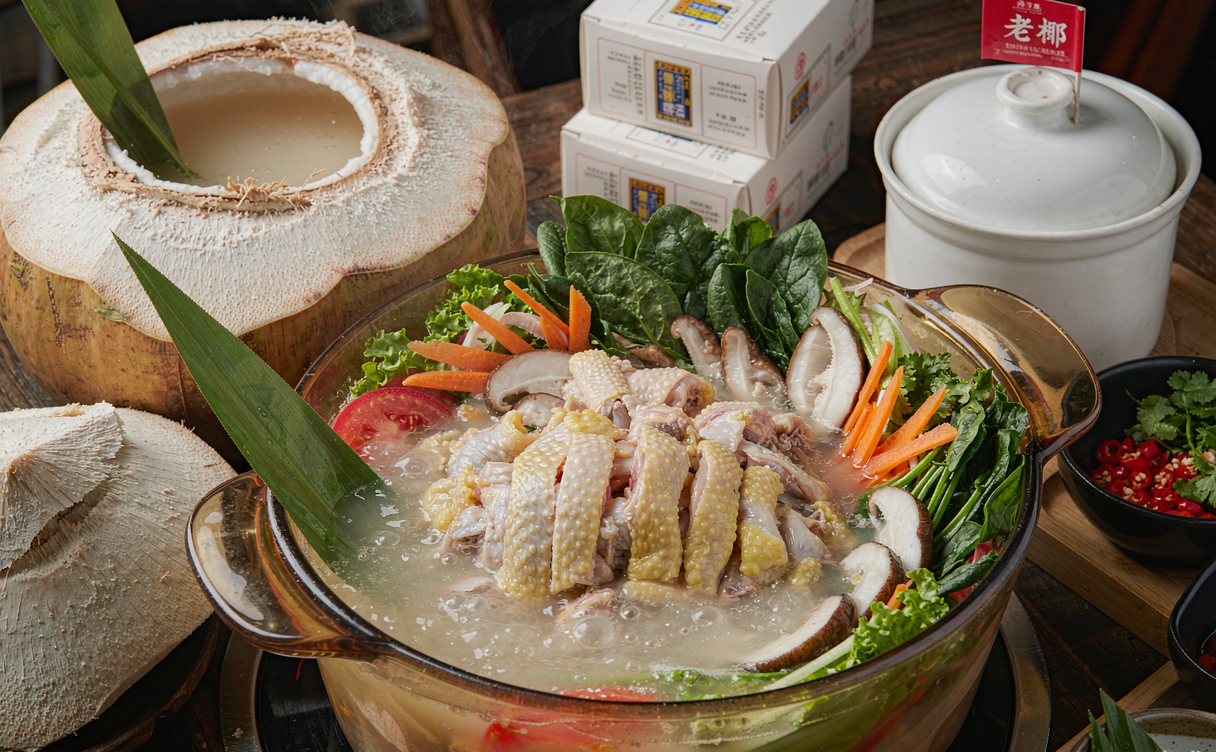 A Haikou restaurant coconut chicken hotpot bubbling with young coconut halves and chicken pieces