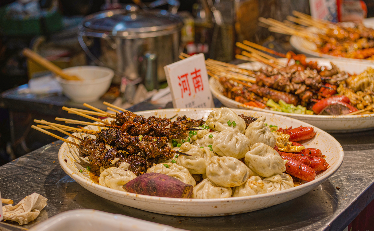 Steamed buns and sizzling lamb skewers at a crowded Kaifeng night market stall in Henan