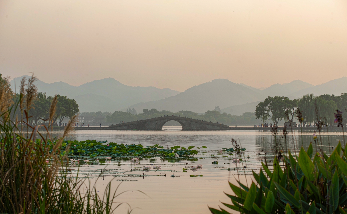 Lakeside hotel terrace with willow trees overlooking West Lake Hangzhou at dawn