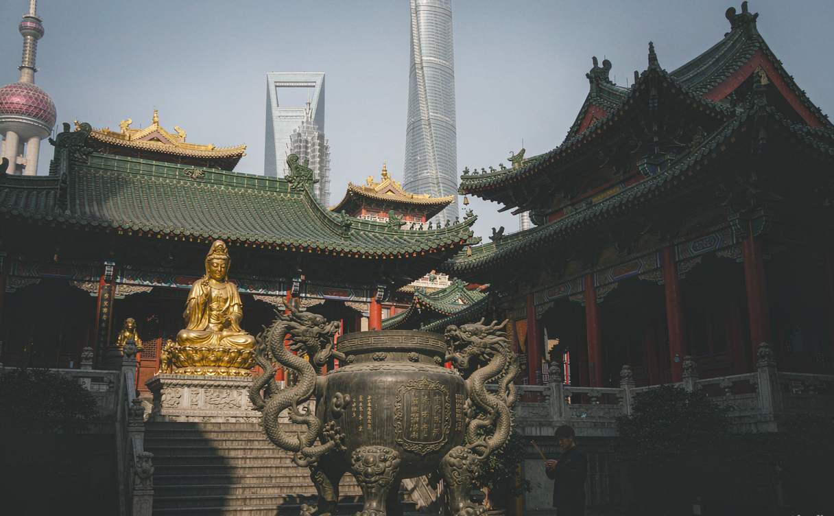 Lit golden rooftops of Jing'an Temple above Shanghai's West Nanjing Road at night, China