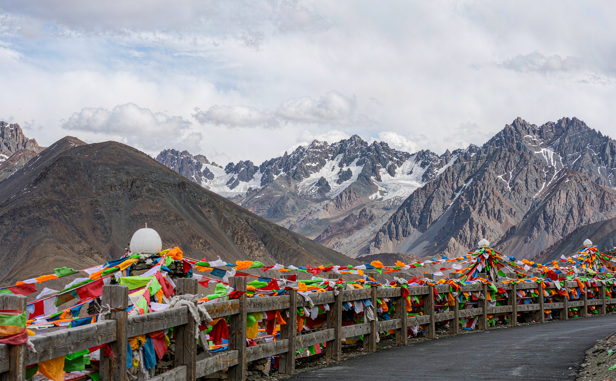 Prayer-flag overlook deck at Kunlun Mountain Pass with glacier peaks of the Kunlun range behind