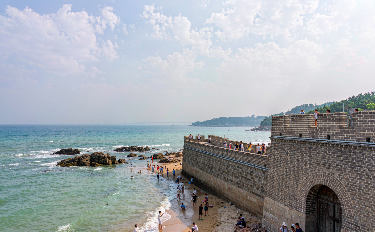Laolongtou Great Wall rampart extending into the Bohai Sea with waves breaking against the stone base