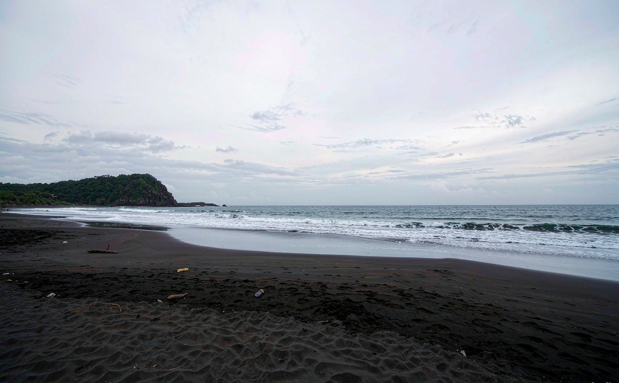 Empty black-sand beach on the Ledong coast with calm shallow water