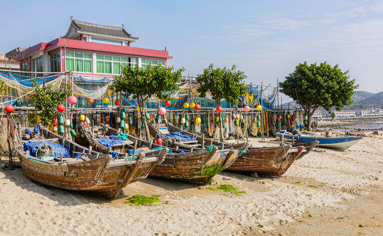 Fishing boats moored at a Lingao harbour at first light with nets drying on the quay