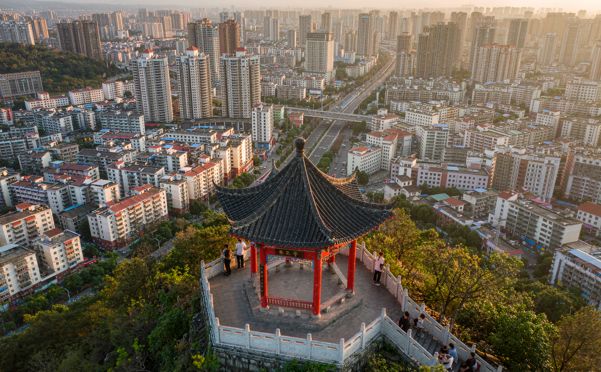 Red wooden pavilion on Qianling hilltop with a panoramic view of Guiyang city below