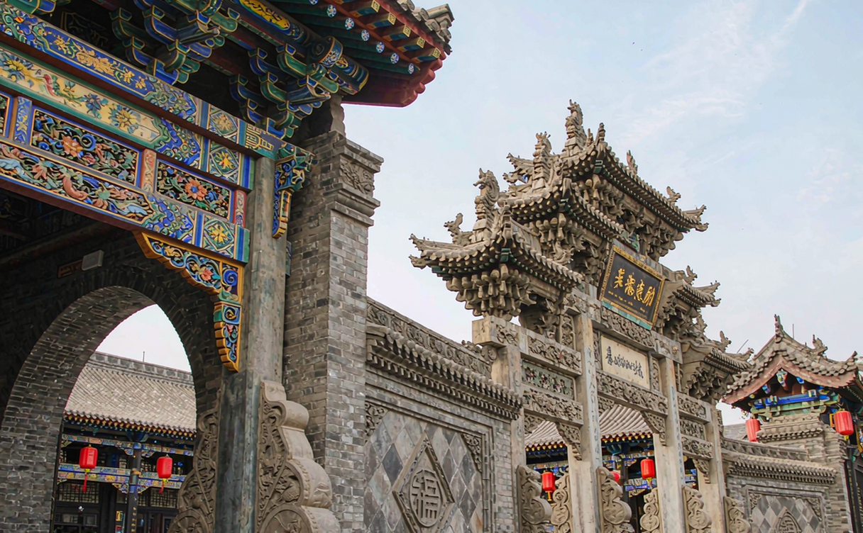 Carved main gate of the Qiao Family Compound in Shanxi, China with grey-brick courtyard walls