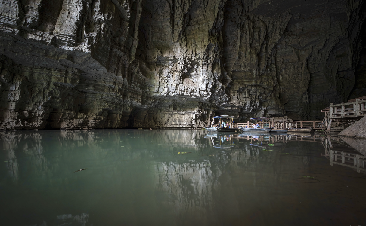 Small boat on the dark underground river inside Tenglong Cave Lichuan