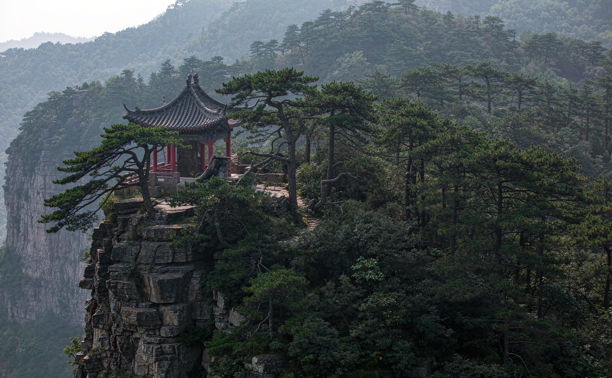 Taoist Yangtai Palace courtyard on Wangwu Mountain with upturned roofs against the wooded peak