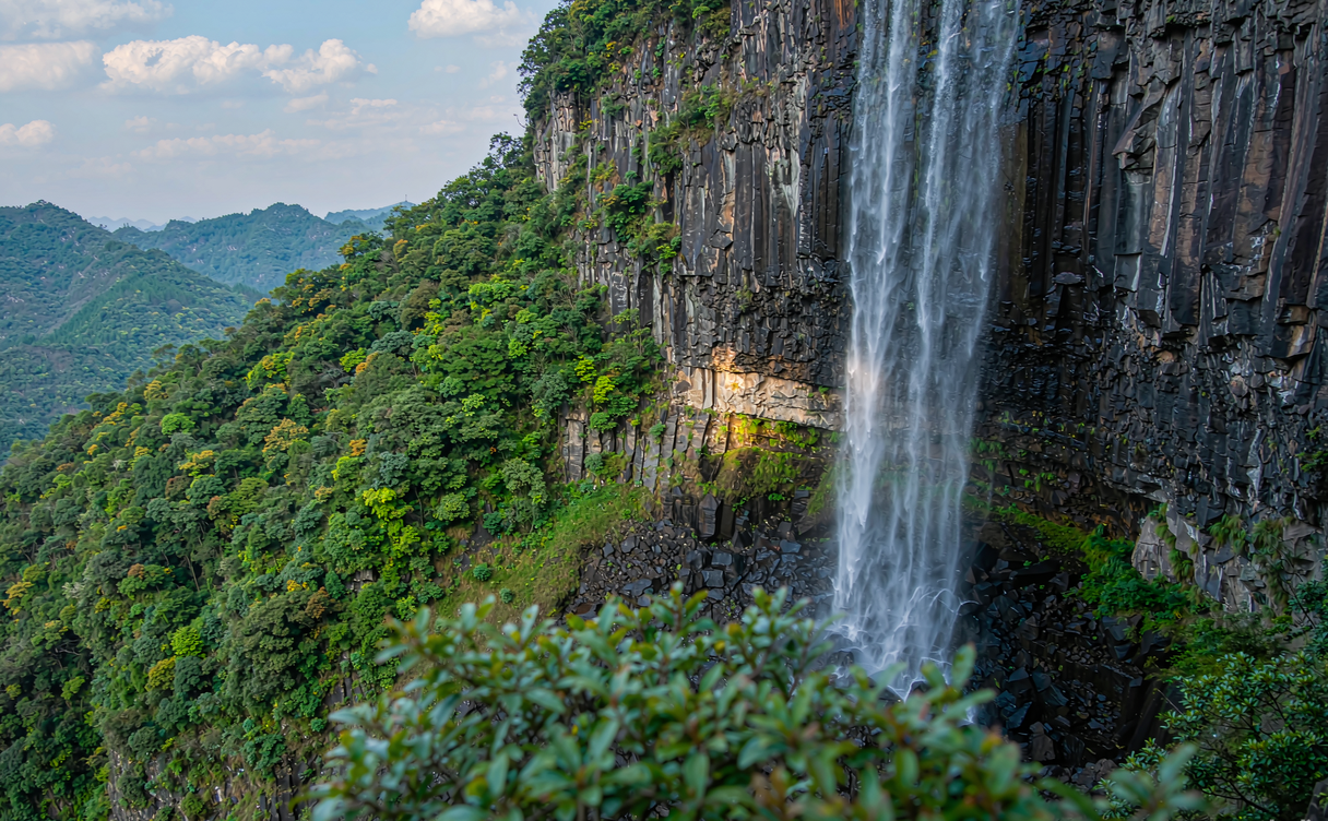 Waterfall plunging over basalt cliffs at Xiqiao Mountain