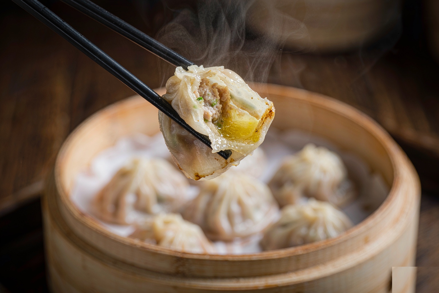 Xiaolongbao broken open by chopsticks showing hot soup inside