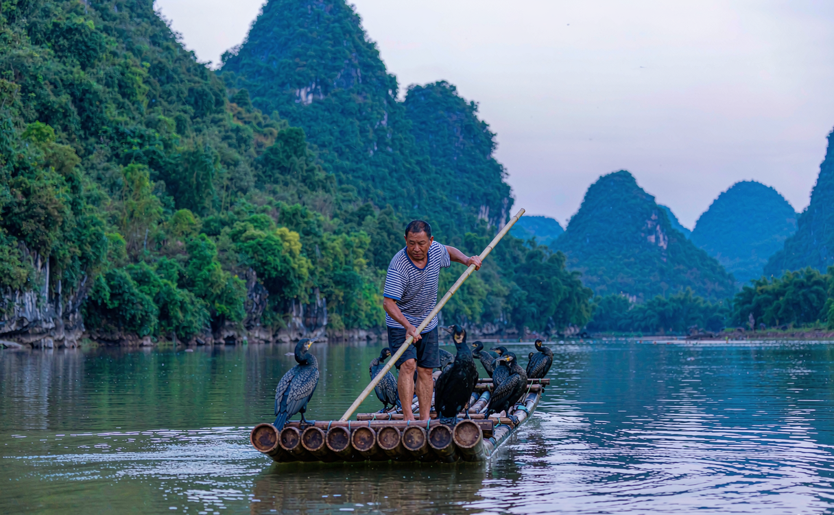 Fisherman on a bamboo raft at Dongjiang Lake