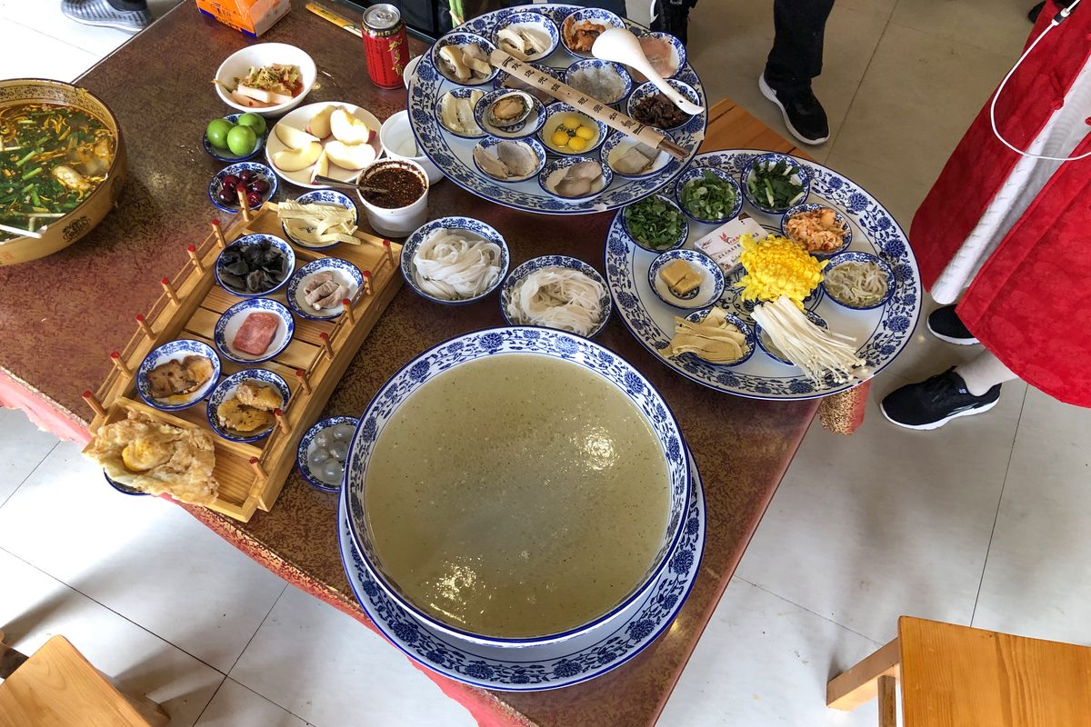 Crossing-the-bridge rice noodles laid out with the full set of raw toppings and broth in Mengzi, Yunnan