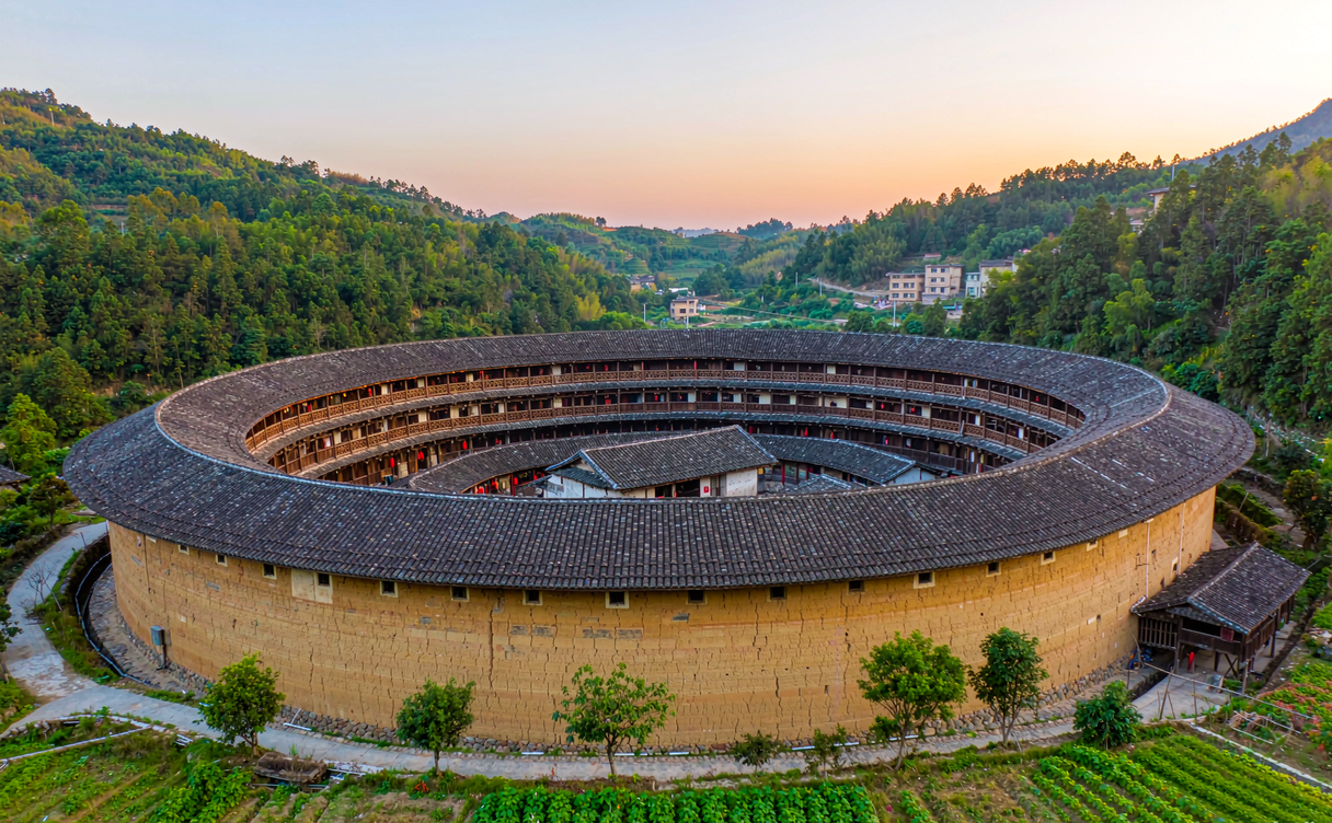 Round Hakka tulou earthen house surrounded by rice fields