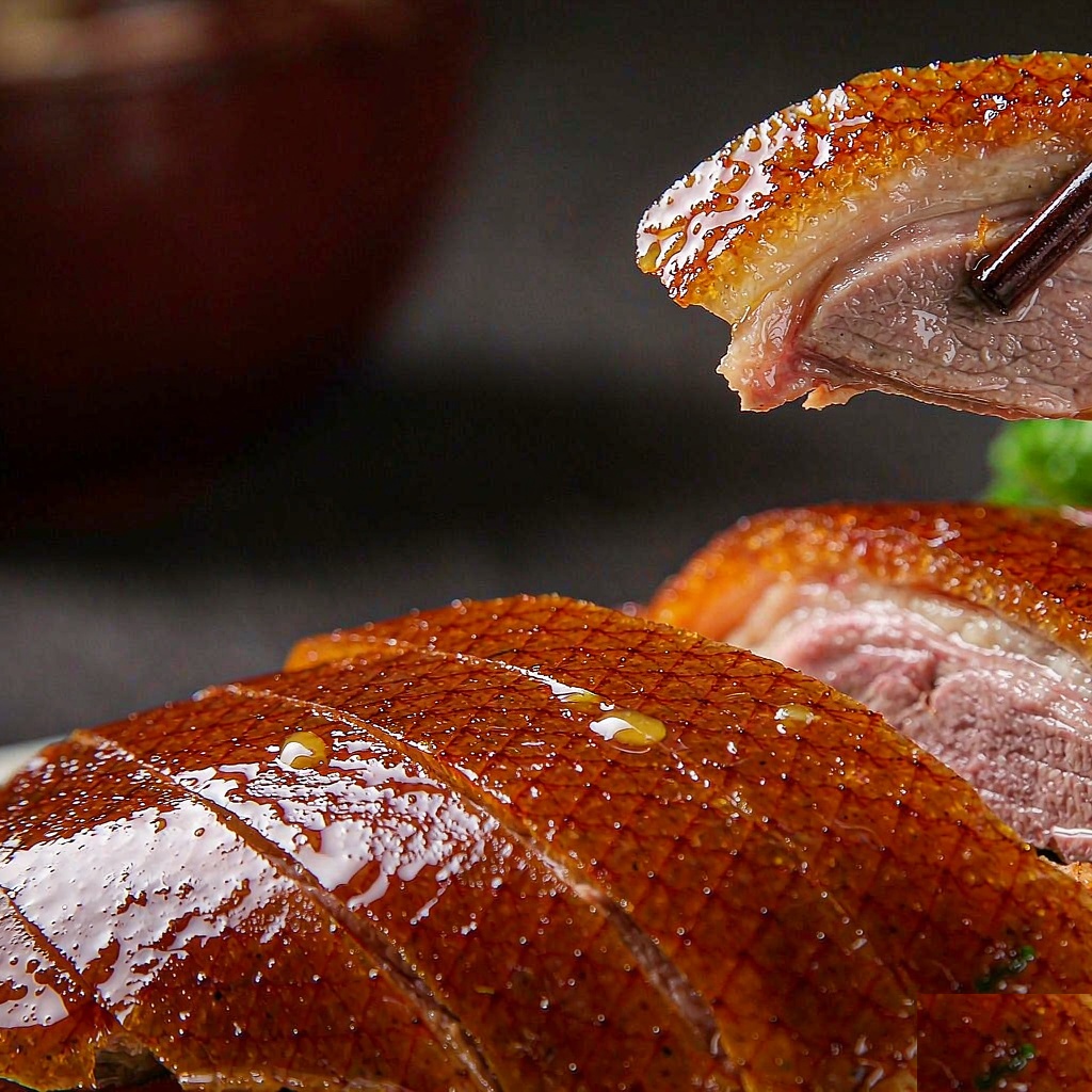 Close-up of a slice of crispy Peking duck skin held in chopsticks above the carved bird