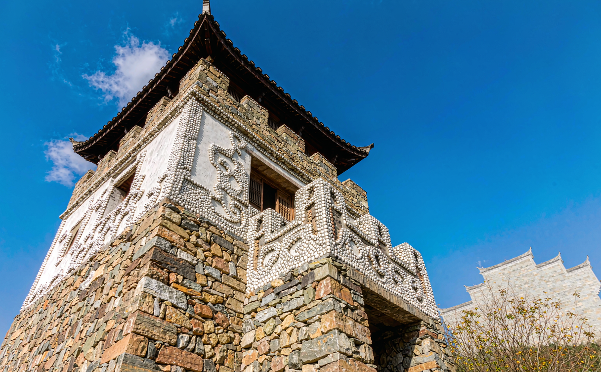 Stone Qiang tower house with white shrine stones on the roof ridge