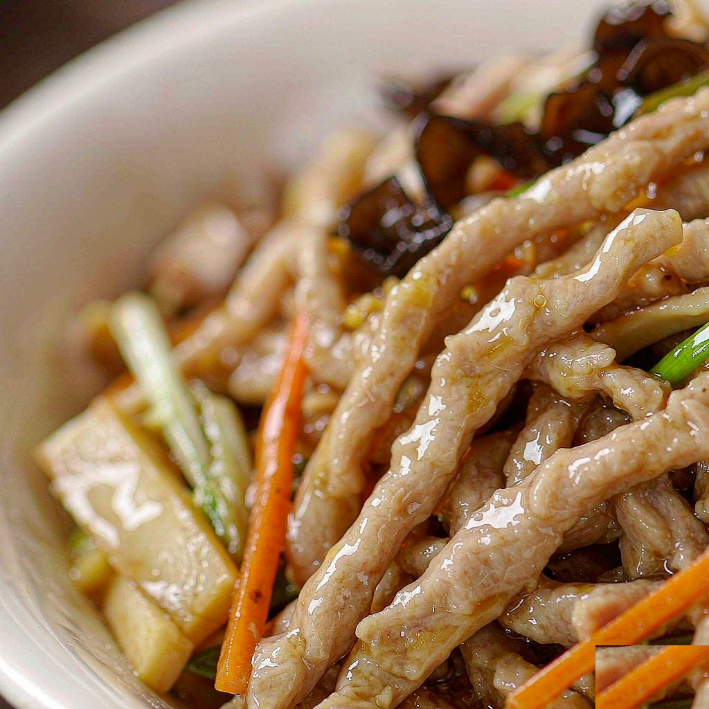 Close-up of silky shredded pork coated in glossy yu xiang sauce with wood ear mushrooms and julienned vegetables