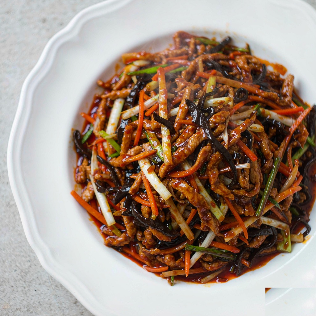 Plate of glossy Sichuan yu xiang shredded pork with carrots, bamboo shoots, wood ear mushrooms and scallions